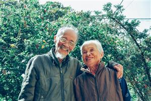 older couple smiling in front of bushes